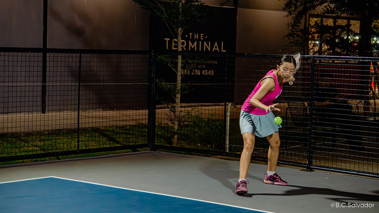 Player hitting a pickleball on court at night