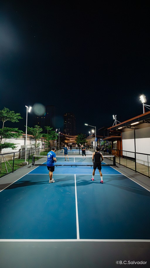Players on a lit outdoor pickleball court at night